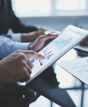 Image of businessperson pointing at document in touchpad at meeting